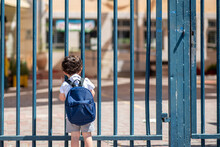 Kid With School Backpack Look On Schoolyard Towards An Open Entrance Or Exit Door. Schools And Preschools Remain Locked For Children During Lockdown, Coronavirus Pandemic And Second Wave Of Covid-19.