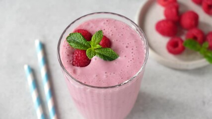 Wall Mural - Raspberry smoothie in a glass. Male hand put glass of pink berry smoothie on a table