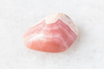 closeup of sample of natural mineral from geological collection - polished Rhodochrosite rock on white marble background from Argentina