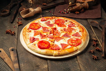 Wall Mural - Pizza with ham and tomatoes on the wooden table
