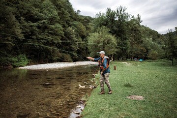 Senior man is fishing alone on fast mountain river. Active people and sport fly fishing concept.