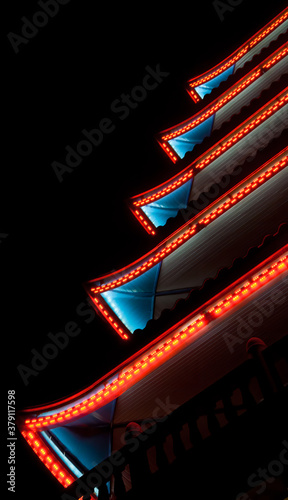 Fotomural Neon patterned lighting of a pagoda with red and blue lighting on a black background