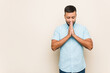 © Asier - Young south-asian man holding hands in pray near mouth, feels confident.