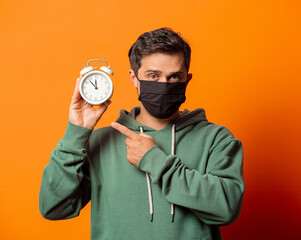 Wall Mural - guy in face mask and green hoodie with alarm clock