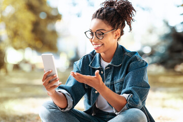 Black Woman Making Video Call On Phone Sitting Outdoors