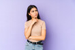 © Asier - Young indian woman isolated on purple background looking sideways with doubtful and skeptical expression.