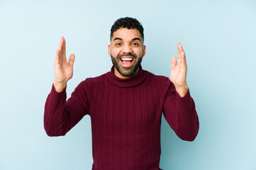 Wall Mural - Young mixed race arabic man isolated receiving a pleasant surprise, excited and raising hands.