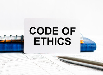 Poster - business card with text code of ethics lying on blue notebook