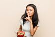 © Asier - Young asian woman holding a cereals bowl keeping a secret or asking for silence.