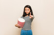 © Asier - Young asian girl holding a popcorn bucket showing number one with finger.