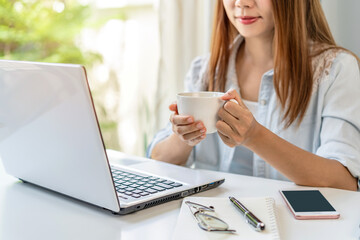 Wall Mural - Young woman taking a coffee break and relaxing at living room while working at home, Work from home concept