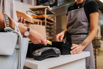 Paying with her credit card in a bakery shop, making a purchaise