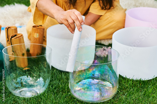 Fotografía Woman playing music on crystal singing bowls, relaxing in beautiful green garden