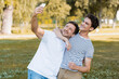© LIGHTFIELD STUDIOS - teenager son hugging father while taking selfie in park