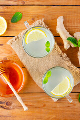 Wall Mural - Ginger tea with lemon and honey. Two cups of ginger tea with mint on wooden background. Top view