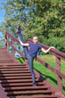© Андрей Рыков - Beautiful ten year old caucasian girl stands on wooden stairs in city park doing standing split on sunny morning. Outdoor sport theme.
