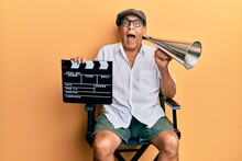 Handsome Mature Director Man Holding Video Film Clapboard And Louder Celebrating Crazy And Amazed For Success With Open Eyes Screaming Excited.