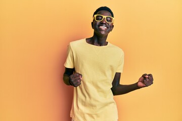 Young african american man wearing casual clothes and glasses excited for success with arms raised and eyes closed celebrating victory smiling. winner concept.