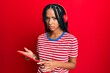 © Krakenimages.com - Beautiful hispanic woman using touchpad device listening to music wearing headphones skeptic and nervous, frowning upset because of problem. negative person.