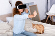 © LIGHTFIELD STUDIOS - Selective focus of woman playing video game in vr headset near cat in bedroom