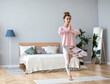 © BestForYou - Beautiful woman with hair bun in sportswear practicing yoga at home, doing Vrksasana exercise on one leg, hands in prayer namaste gesture, Tree pose.