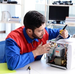 Young repairman fixing and repairing microwave oven