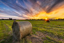 Beautiful Sunset Over Green Meadow With Hay Bales