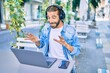 © Krakenimages.com - Young middle eastern man doing video call using laptop and headphones at coffee shop terrace.