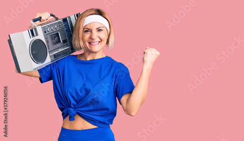 Fotografía Young blonde woman wearing sportswear holding boombox, listening to music scream