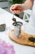 © JacZia - Making a perfect loose tea. Putting tea leaves by a teaspoon into a tea infuser in a glass teapot.