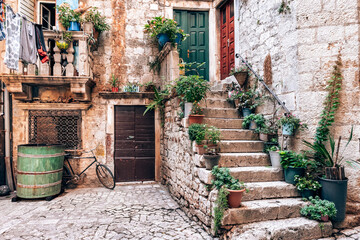 Wall Mural - Picturesque street in Trogir city with flower pots and fresh laundry