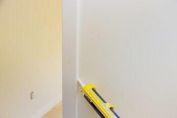 Canvas Print - Worker hands on applying silicone sealant with caulking gun for repairing door molding trim