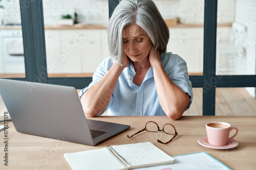 Fotografía Tired stressed old mature business woman suffering from neckpain working from home office sitting at table