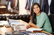 © DragonImages - Portrait of happy young Indian atelier owner working on laptop