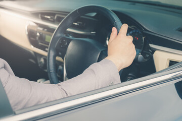 Businessman driving the luxury car on his morning commute to work. The handsome man's hand touched the steering wheel of his automobile with confidence in his road trip.