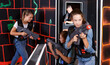 © JackF - Fine girl aiming laser gun at other players during laser tag game in dark room