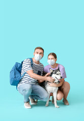 Sticker - Young couple with medical masks and cute Husky dog on color background. Concept of epidemic