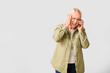 © Pixel-Shot - Stressed mature woman talking by phone on light background