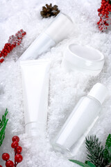 Wall Mural - Cosmetics concept with Christmas decor on a snow. Winter moisturizing care for sensitive skin. A set of micellar water, face and body cream, cleansing skin lotion, skincare. Personal hygiene products