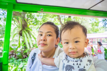 Wall Mural - Shot of Mother and her little son sit on tram in summer day at the zoo. Concept of friendly family and vacation