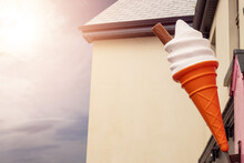Big Plastic Ice Cream Cone In A Waffle Outside Shop Against Bright Wall And Sunny Warm Sky.