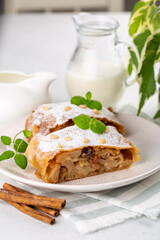 Sticker - Apple strudel with raisins,  peanuts and cinnamon. A jug of milk.  Light background.