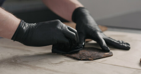 Poster - man hands applying oil finish on dark cork coaster