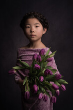 Portrait Of Teenage Girl With Bouquet Of Purple Tulips Standing Indoors