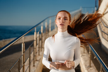 Wall Mural - Image of redhead sportswoman running on staircase while working out