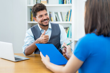 Latin american businessman and female trainee signing contractat after job interview