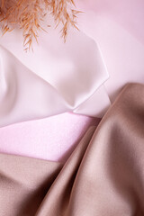 Abstract background in soft colors of silk fabrics on pink pearl paper and branch Dry beige reed. Beautiful trend texture