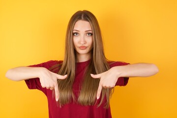 beautiful young beautiful caucasian girl wearing red t-shirt over isolated yellow background pointin