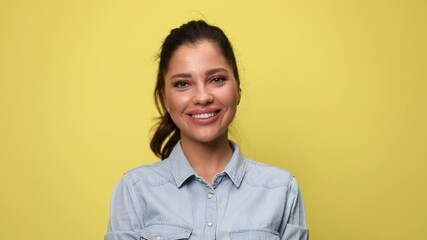 Wall Mural - attractive young casual girl in blue denim shirt smiling and posing on yellow background