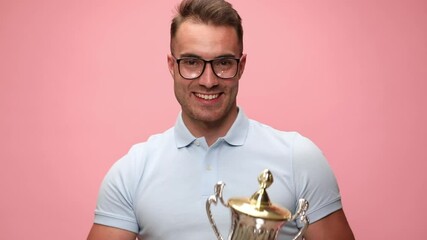 Poster - attractive casual man hiding behind his cup, celebrating succes, raising his cup in the air and celebrating succes on pink background